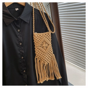 Detail of bohemian straw bag featuring woven diamond patterns and long decorative tassels