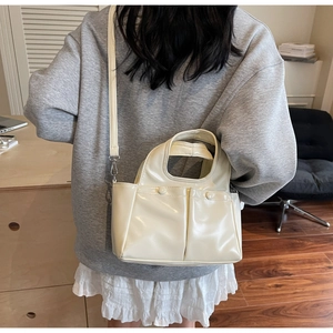 Detail view of a cream PU leather tote bag with double pockets worn by a model
