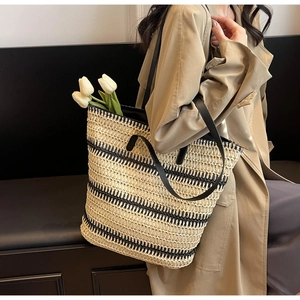 Détail du sac cabas en paille tissée à rayures beige et noir avec lanières en cuir sur mannequin