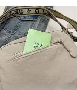 Détail du sac bandoulière en nylon beige avec poche zippée et sangle tissée logo