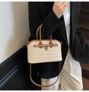 Close-up of woven straw handbag with brown leather trim and silver metal twist lock