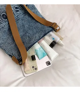 Macro view of large capacity denim tote bag showing tablet and cosmetics inside