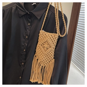 Detail of woven straw crossbody bag with intricate diamond texture and long fringe accents