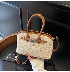 Detail of woven straw handbag with brown leather trim and silver metal lock on black chair