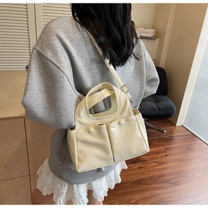 Detail of cream pleated tote bag featuring two front pockets and detachable shoulder strap