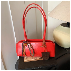 Vue détaillée du sac baguette rouge avec deux fines poignées et rubans en cuir décoratifs