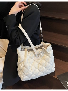 Weiße Stepp-Tote-Bag mit silberner Kette, von Model auf Treppen getragen für einen Look