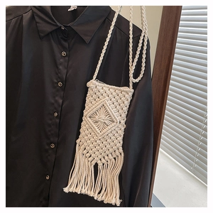 Detailed close-up of cream handmade woven cotton bag with bohemian fringe and diamond texture