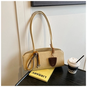 Détail d'un sac baguette beige minimaliste avec cordon en cuir sur une table