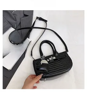 Close-up of black crocodile pattern handbag with silver twist lock and heart pendant