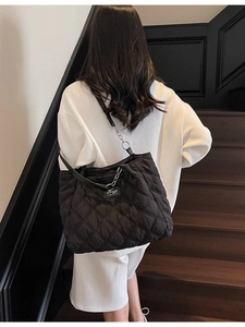 Große gesteppte schwarze Tragetasche mit silberner Kette am Modell in urbanem Design