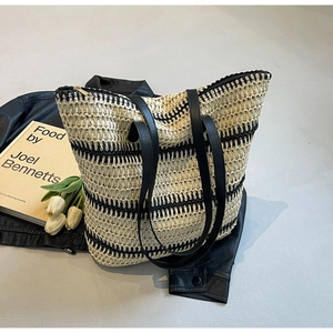 Détail du sac cabas tissé à rayures noires avec anses en cuir sur fond élégant