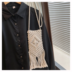 Macro shot of white hand-woven bohemian bag featuring diamond patterns and long fringe tassels