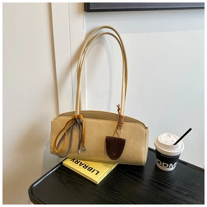 Sac baguette beige avec pendentif cœur sur un livre de bibliothèque et un café