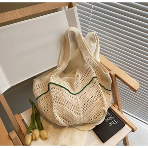 Detail of crochet tote bag featuring beige hollow knit texture and green wavy trim edges