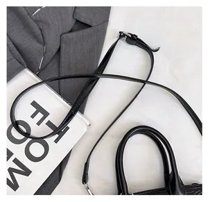Close-up of black faux leather handbag featuring crocodile pattern and silver metal hardware