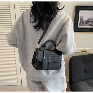 Detail of black crossbody bag featuring mixed leather texture and fashion brand tag