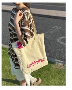 Détail du sac cabas en nylon beige avec inscription LanShaWan rouge et étiquette tissée
