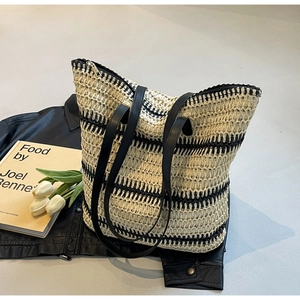Détail du sac cabas tissé à rayures minimaliste avec anses en similicuir sur une veste en cuir