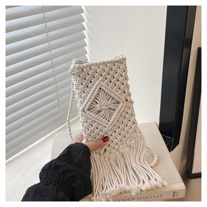 Close-up of hand-woven straw phone bag with elegant diamond knots and long tassels