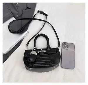 Size comparison of a black crocodile pattern half-moon bag next to an iPhone