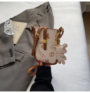 Detail of beige crossbody bag with vintage bear print beside a grey suit blazer
