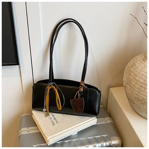 Gros plan du sac baguette rétro noir avec texture cuir et détails de ruban en soie