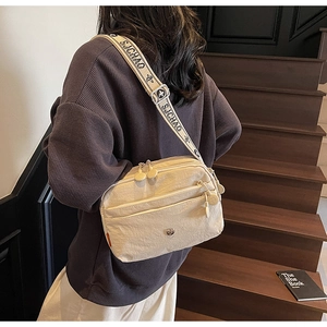Détail du sac bandoulière en nylon beige avec sangle réglable large porté par un mannequin