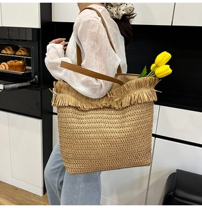 Macro view of woven straw tote bag with long fringe tassels and leather handles