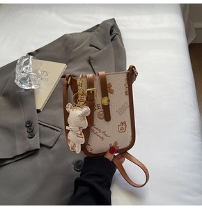 Detail of cream crossbody phone bag with Keddy Bear prints and gold metal hardware