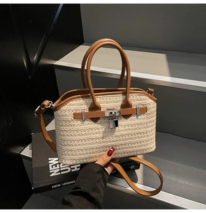 Detail of woven straw handbag with brown leather straps and elegant metal lock closure
