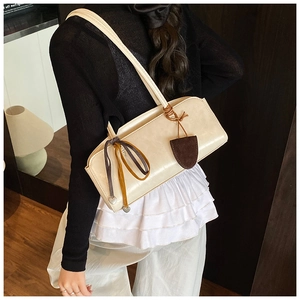 Détail du sac baguette crème avec ruban coloré et pendentif décoratif marron élégant