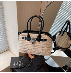 Close-up of woven straw handbag with black leather trim and silver metal padlock detail