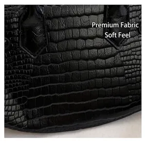 Detail of black crocodile embossed handbag with teardrop stitching on leather handles