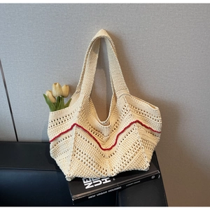 Macro view of hand-woven cream tote bag with vibrant red zigzag wave crochet pattern