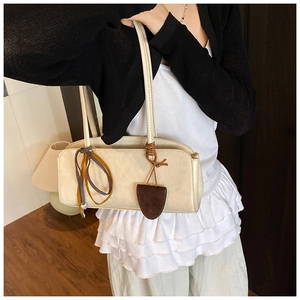 Détail du sac baguette crème minimaliste avec charms en cuir vintage et fines lanières