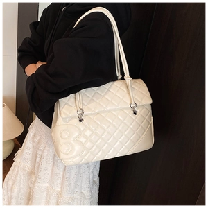 Dettaglio della borsa shopper trapuntata beige con toppa numero otto sulla modella