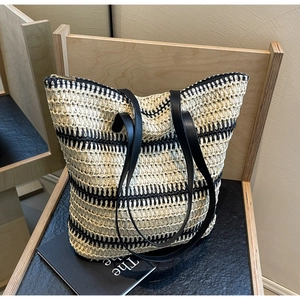 Détail du sac cabas tissé avec rayures beige et noir sur une chaise en bois
