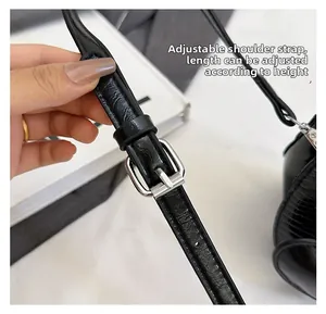 Adjustable black leather strap with silver metal buckle on a small handbag