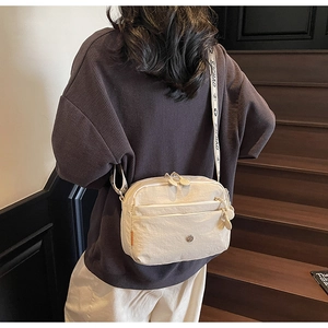 Détail du sac bandoulière crème à poches multiples avec large sangle jacquard
