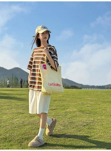 Fille en t-shirt rayé et short blanc avec un grand sac cabas en toile jaune vif