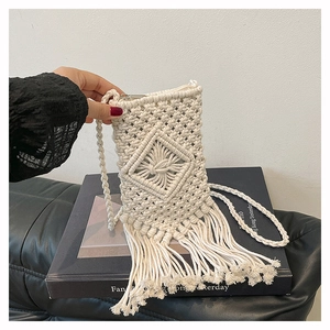 Detail of handmade bohemian woven cotton phone bag with tassel fringe and rhombic pattern
