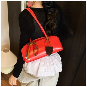 Détail du sac baguette rouge avec étiquette vintage et fine bandoulière d'épaule