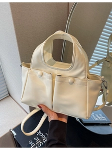Cream white leather tote bag with dual front pockets and adjustable shoulder strap