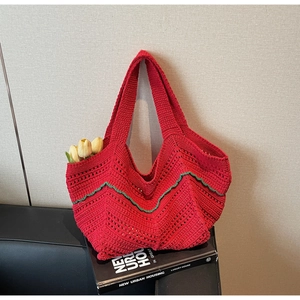 Detail of red hollow-out crochet tote bag featuring green wavy scalloped edges and dual handles