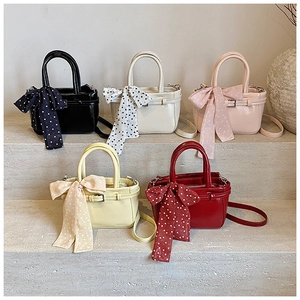 Minimalist square handbags in five colors with polka dot scarves on a stone display