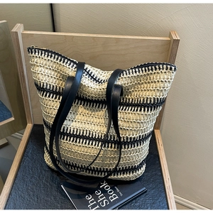 Détail d'un grand sac cabas en paille tressée à rayures bicolores et anses en cuir
