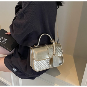 Detailed shot of gold woven texture handbag featuring metallic handle and crossbody strap