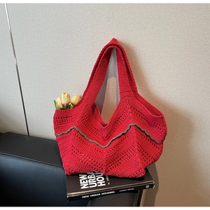 Detail view of red hand-woven tote bag with green wavy stitching and floral accents