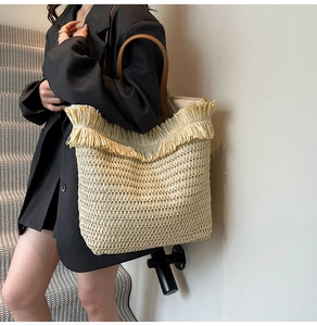 Detailansicht der gewebten Strohtextur und der Ledergriffe an der großen Strandtasche